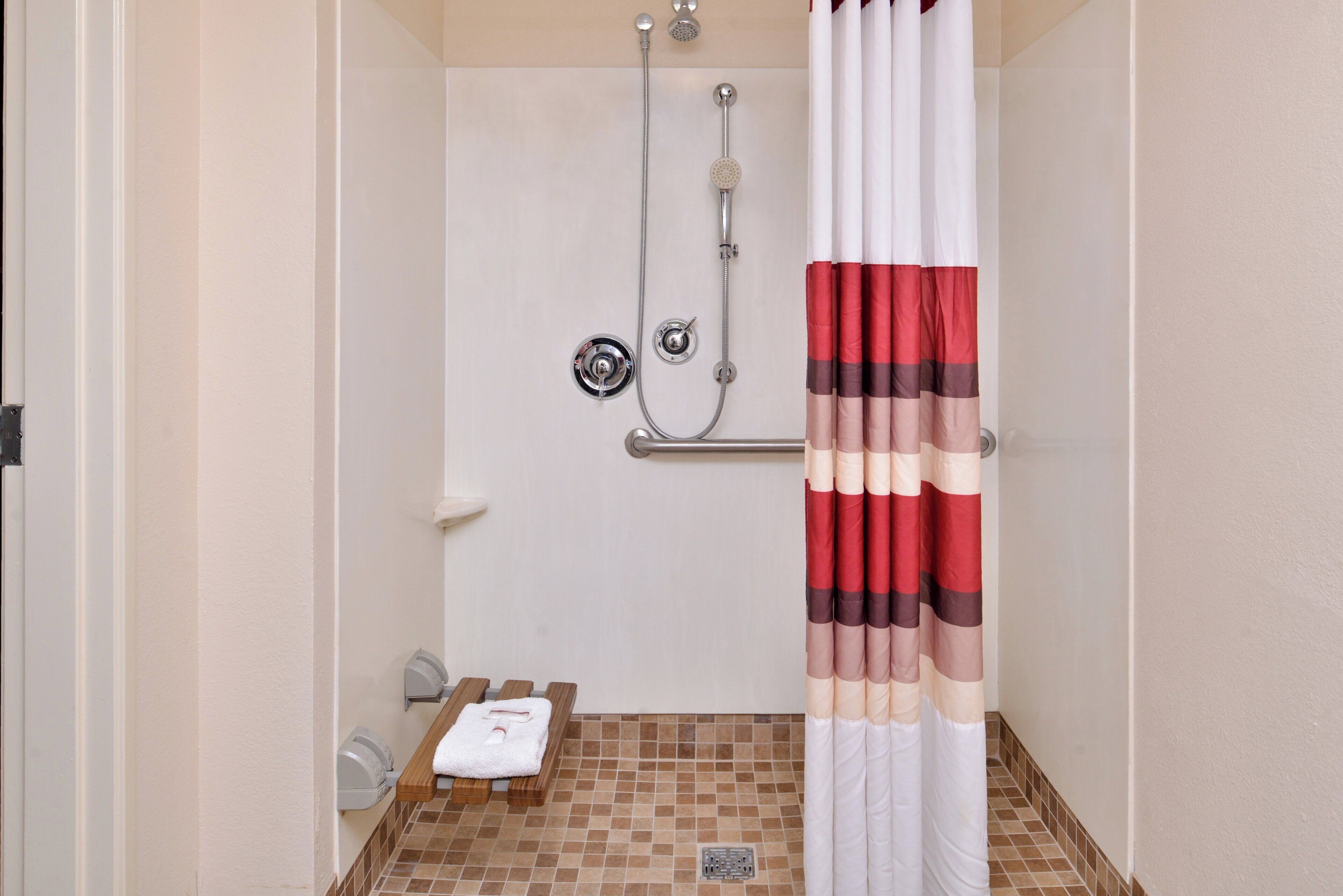 Casa de banho com chuveiro, porta-toalhas e chão em mosaico.
