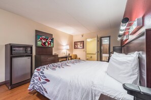 Une chambre d’hôtel équipée d’un lit, d’un bureau, d’un four à micro-ondes, d’une télévision et d’une porte donnant accès à une salle de bain.