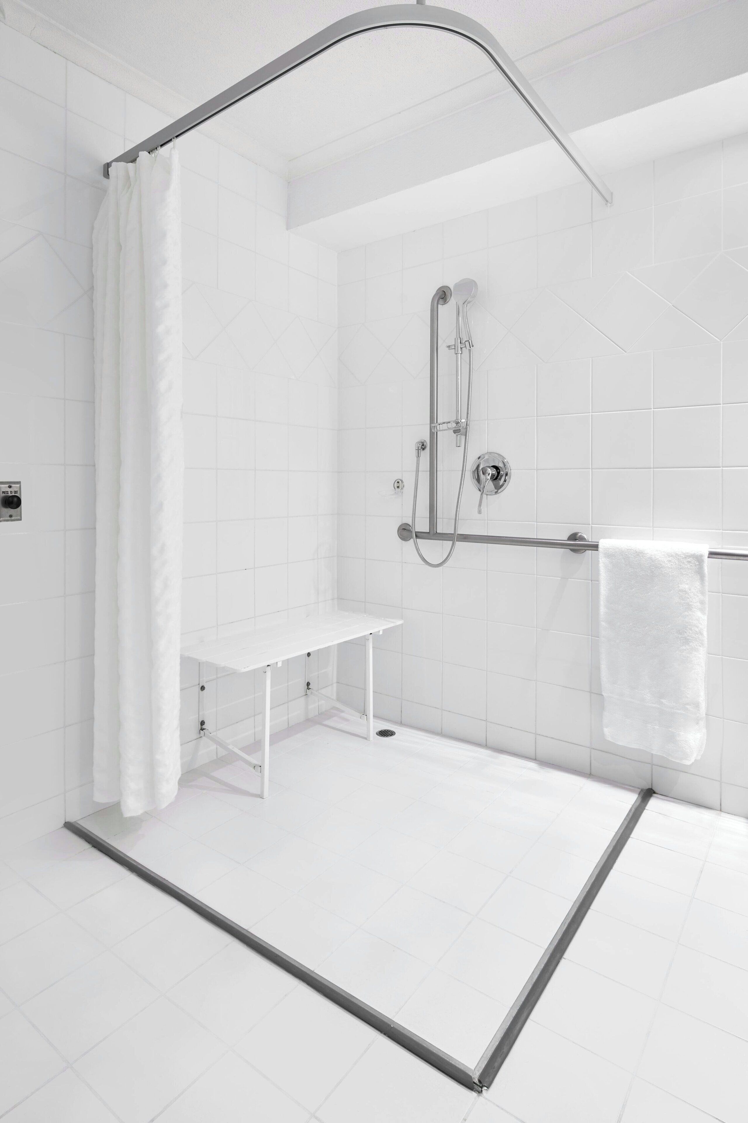 Un área de ducha moderna con puerta de cristal, un banco y un perchero para toallas.