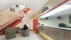 A lobby with a staircase, a reception desk, and patterned furniture. - Days Inn by Wyndham Savannah Airport (Garden City)