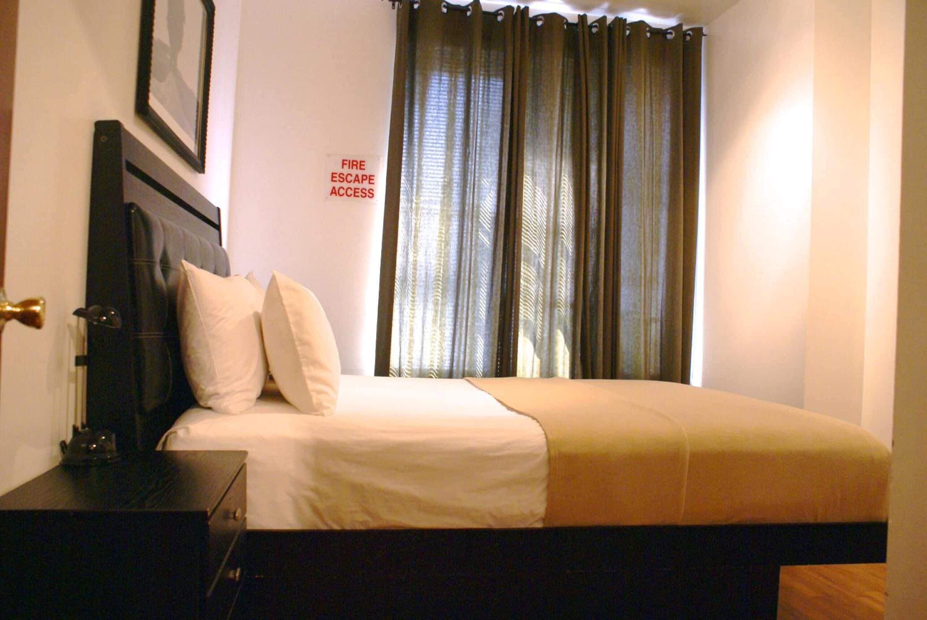 A hotel room with a bed, a nightstand, a lamp, and a sign indicating fire escape access.