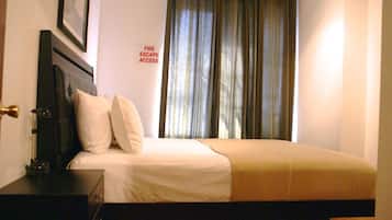 A hotel room with a bed, a nightstand, a lamp, and a sign indicating fire escape access.