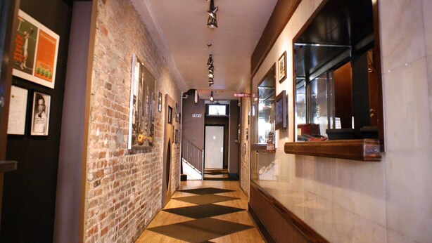 A hallway with a brick wall on one side and a tiled wall on the other, leading to a door labeled "STAIR B". - Off Soho Suites Hotel (New York)