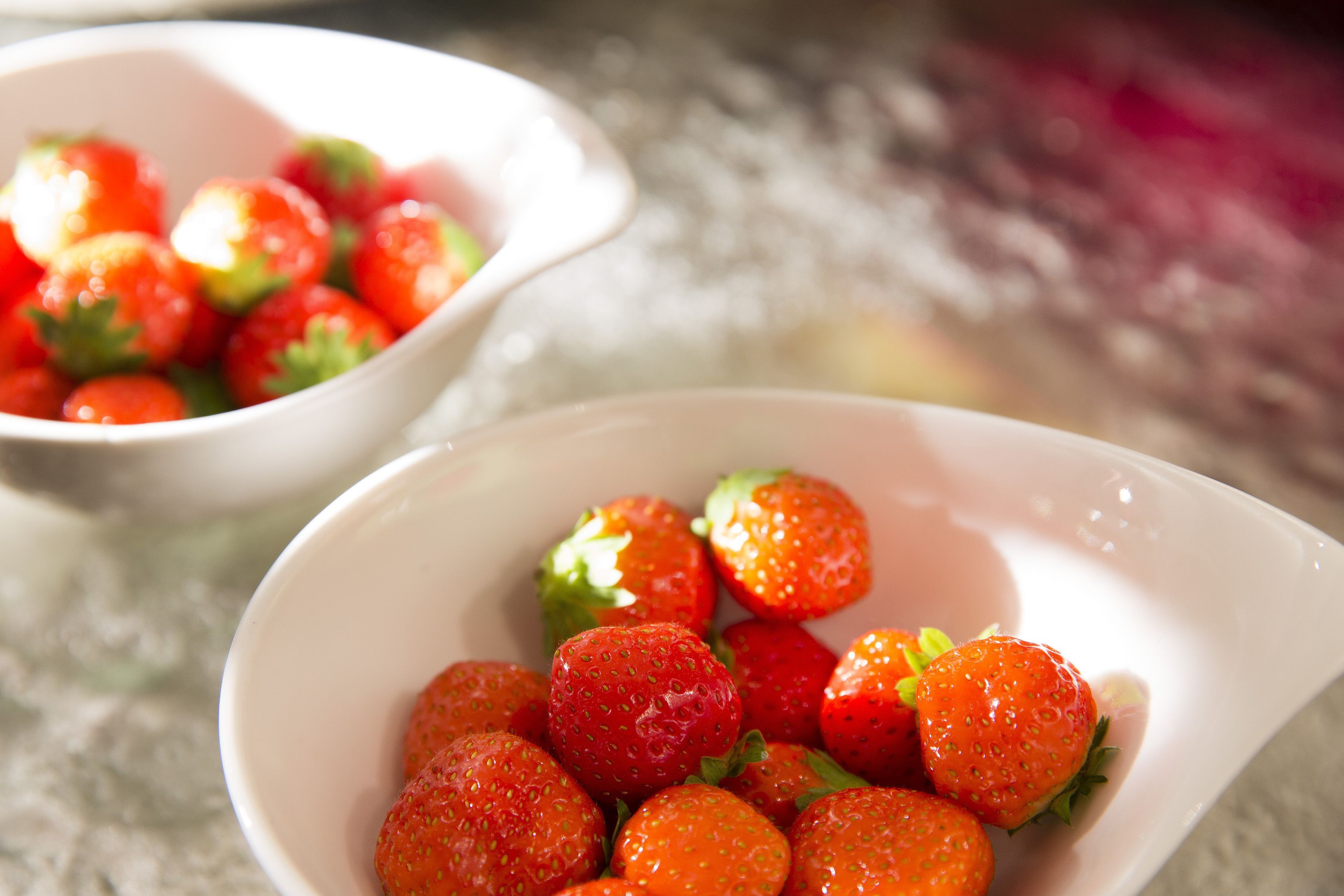 Two white bowls filled with fresh strawberries.
