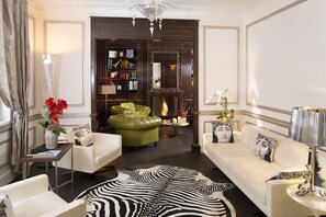 Relax in the elegantly furnished living room with a plush sofa, leather couch, and armchair, anchored by a decorative rug and a fireplace.