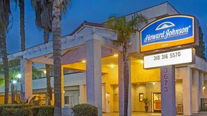 A Howard Johnson Inn with a prominent sign, large pillars, and a well-lit entrance. - Howard Johnson by Wyndham Torrance (Torrance)