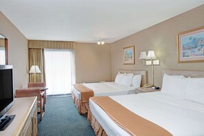 A hotel room with two beds, a desk with a TV, a lamp, and a painting on the wall.