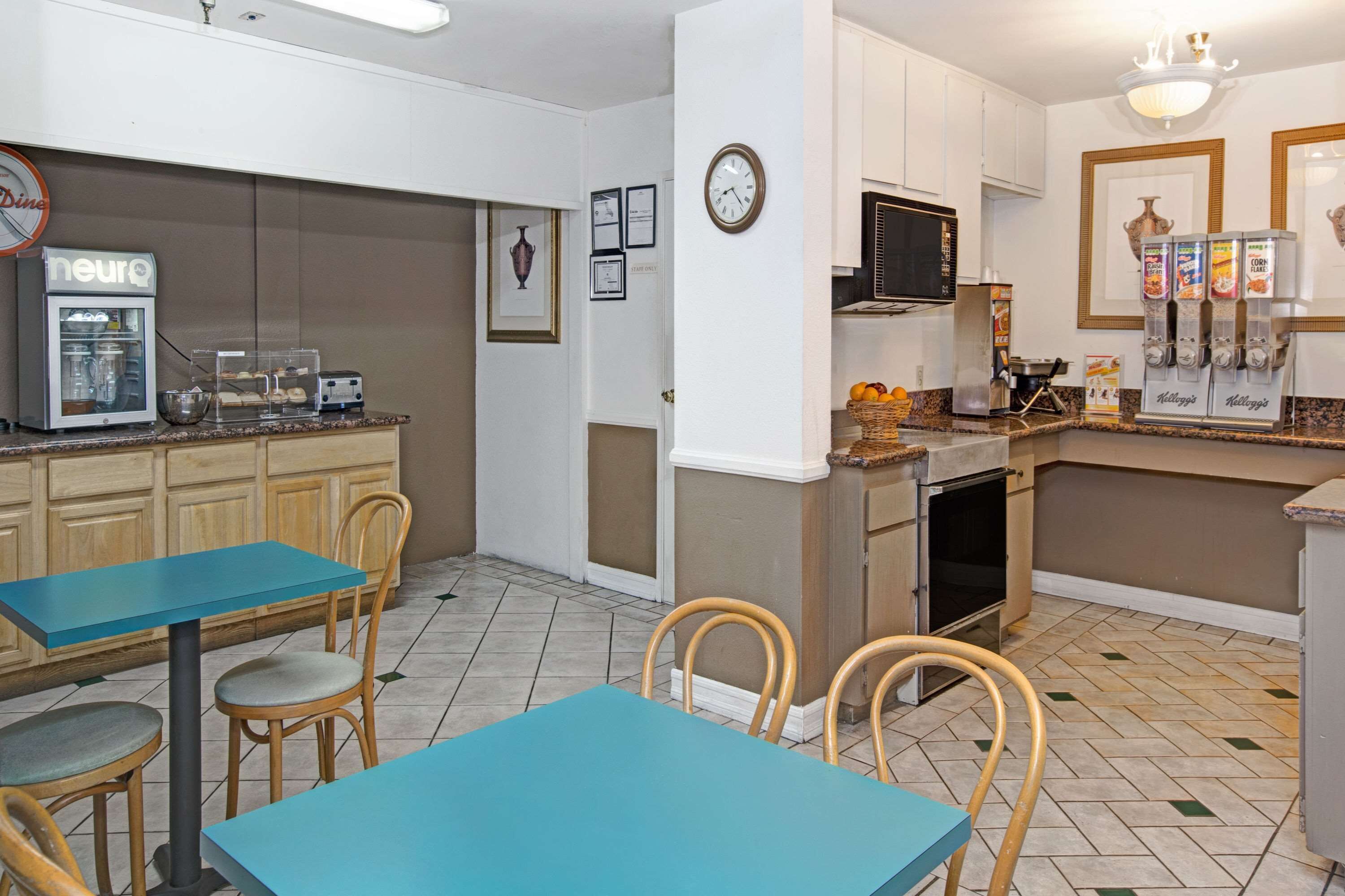 A kitchen with a coffee machine, toaster, and cereal dispenser. There are chairs and a table.