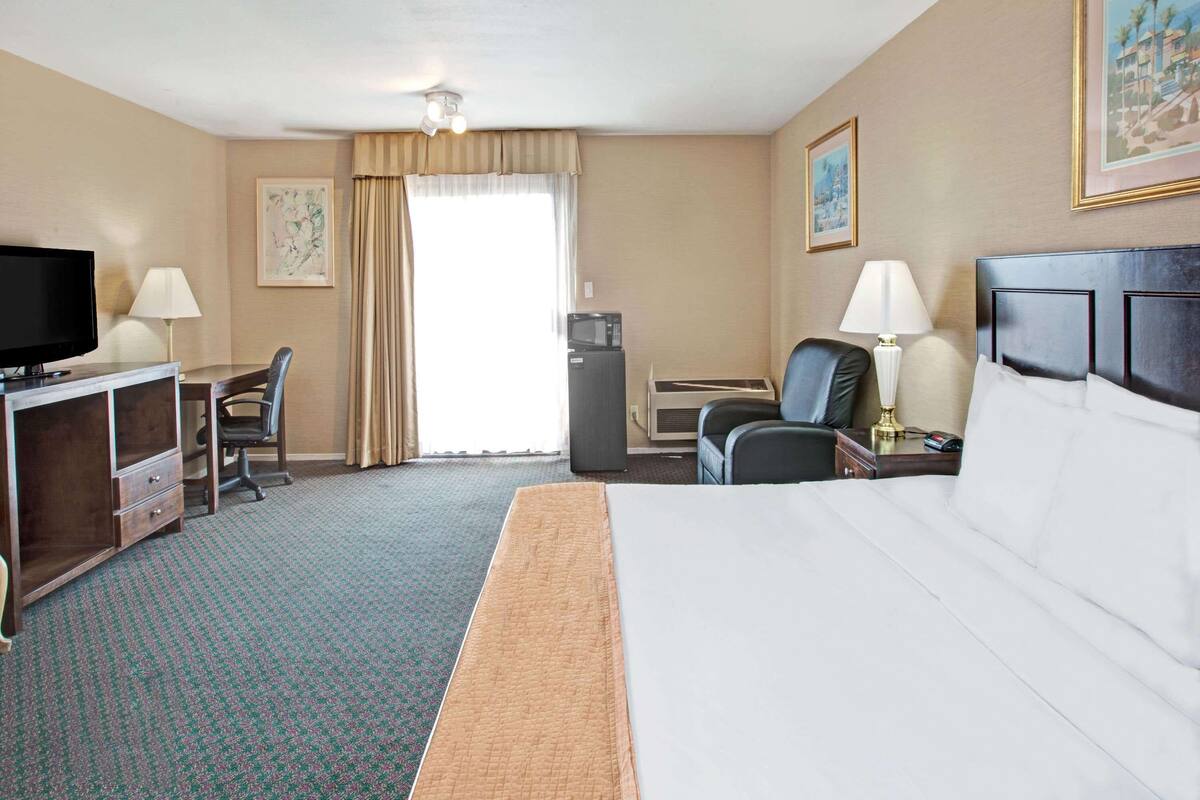 Hotellihuone, jossa on sänky, työpöytä, televisio ja mikroaaltouuni.