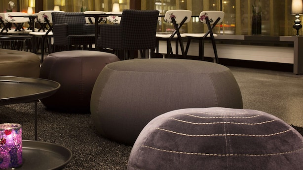 A modern lounge area with plush seating, a glass partition, and hanging light fixtures. - Scandic Copenhagen (Copenhagen)