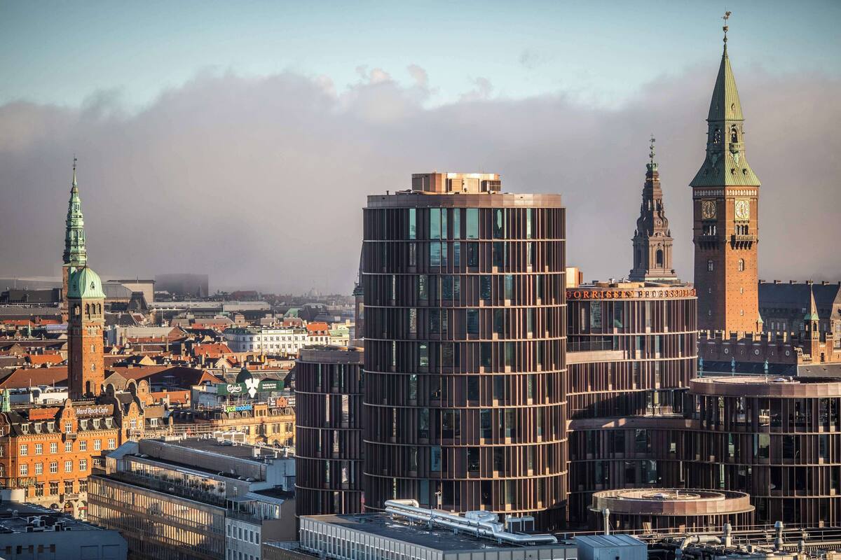 A cityscape with historic buildings and modern architecture, including a prominent clock tower and a modern glass building.