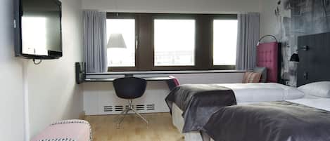 A bedroom with two beds, a desk, a chair, and a TV.