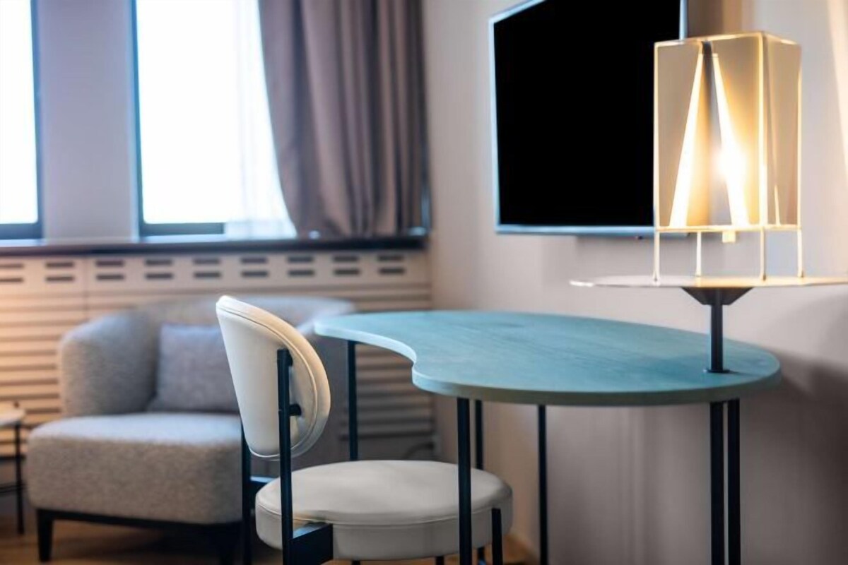 A modern room with a curved teal table, a white chair, and a floor lamp.