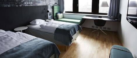 A modern hotel room with two beds, a desk, a chair, and a large window offering a city view.