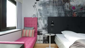 A modern bedroom with a pink sofa, a small bedside table, and a bed with white bedding.