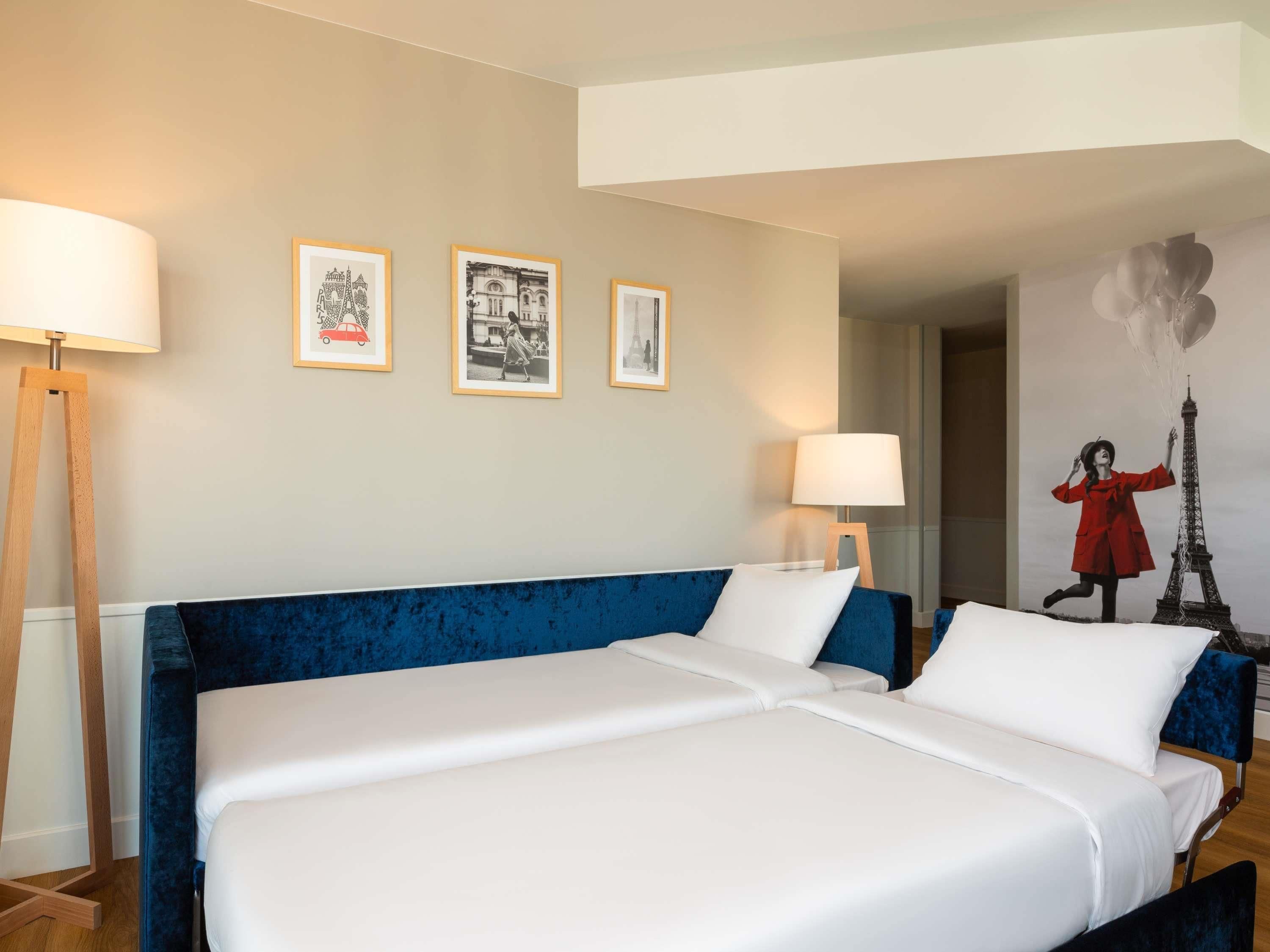 A hotel room with a large bed, two bedside tables, and three framed pictures on the wall.