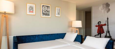 Una habitación de hotel con una cama grande, dos mesitas de noche y tres cuadros enmarcados en la pared.