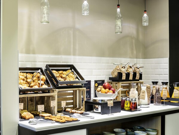 En buffé med ett varierat utbud av mat, inklusive bakverk och frukt, samt en kaffestation med flera olika dryckesalternativ.