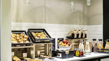 Een buffet met diverse gerechten, waaronder gebak en fruit, plus een koffiecorner met meerdere drankjes.
