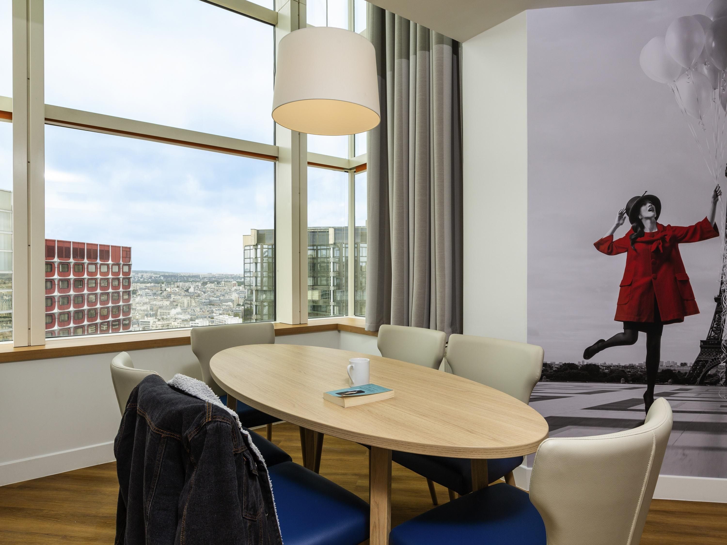 A modern room with a large window, a round table, and a view of the cityscape.