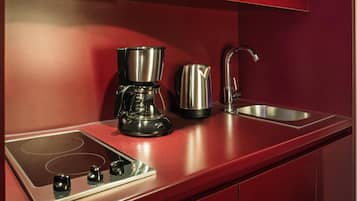 Een moderne keuken met een inbouwfornuis, een koffiezetapparaat, een waterkoker en een roestvrijstalen spoelbak.