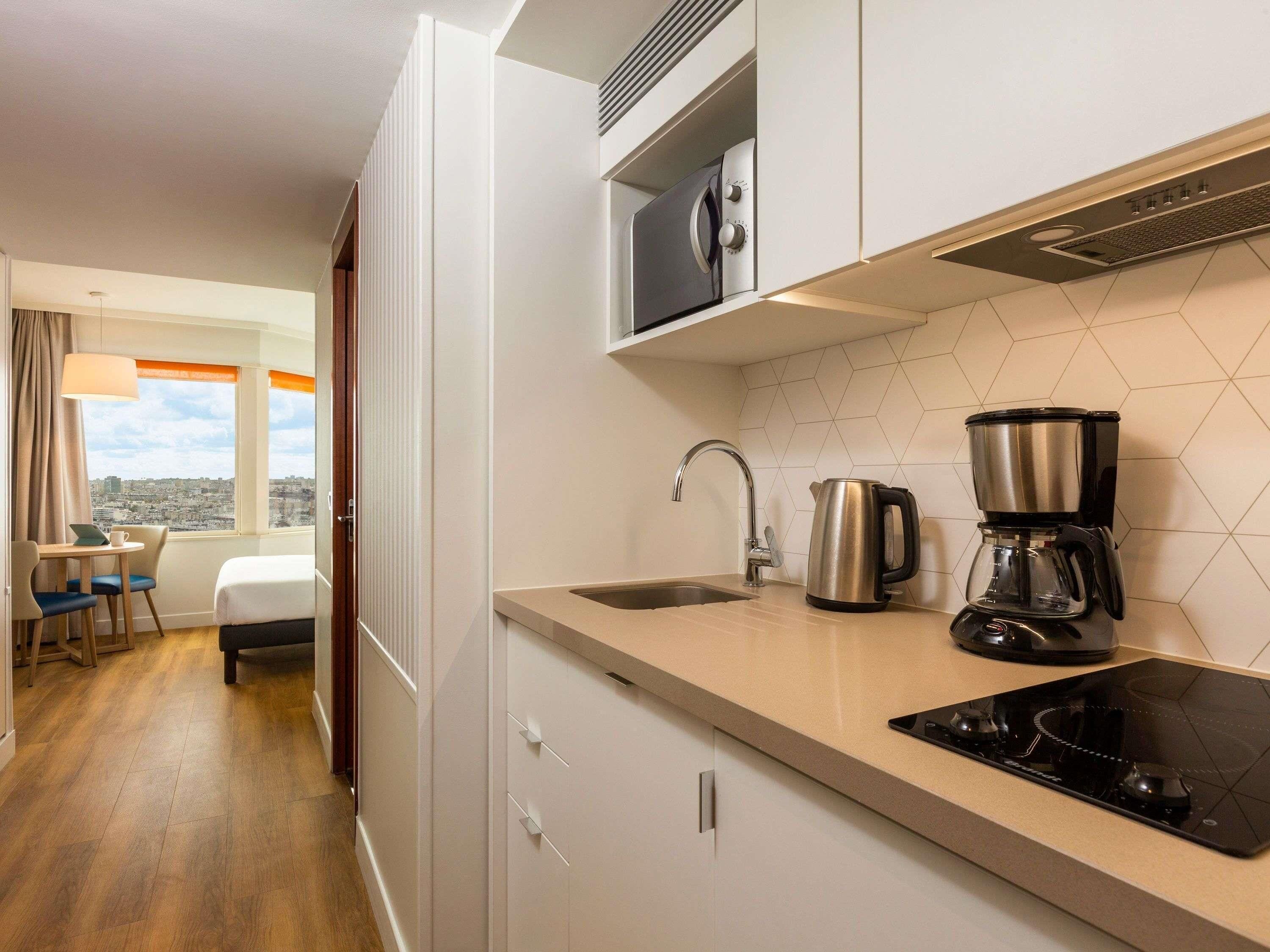 A modern kitchen with a stove, coffee maker, and kettle.