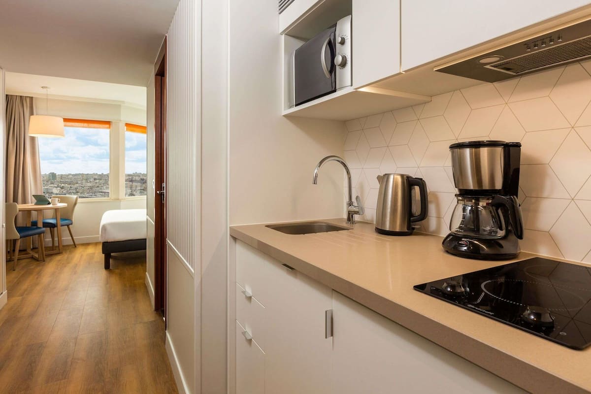 A modern kitchen with a stove, coffee maker, and kettle.