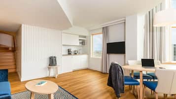 Une chambre d’hôtel moderne dotée d’une cuisine, d’un coin repas et d’une grande fenêtre donnant sur la ville.
