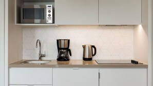 Una cocina moderna con microondas integrado, cafetera y hervidor sobre la encimera.
