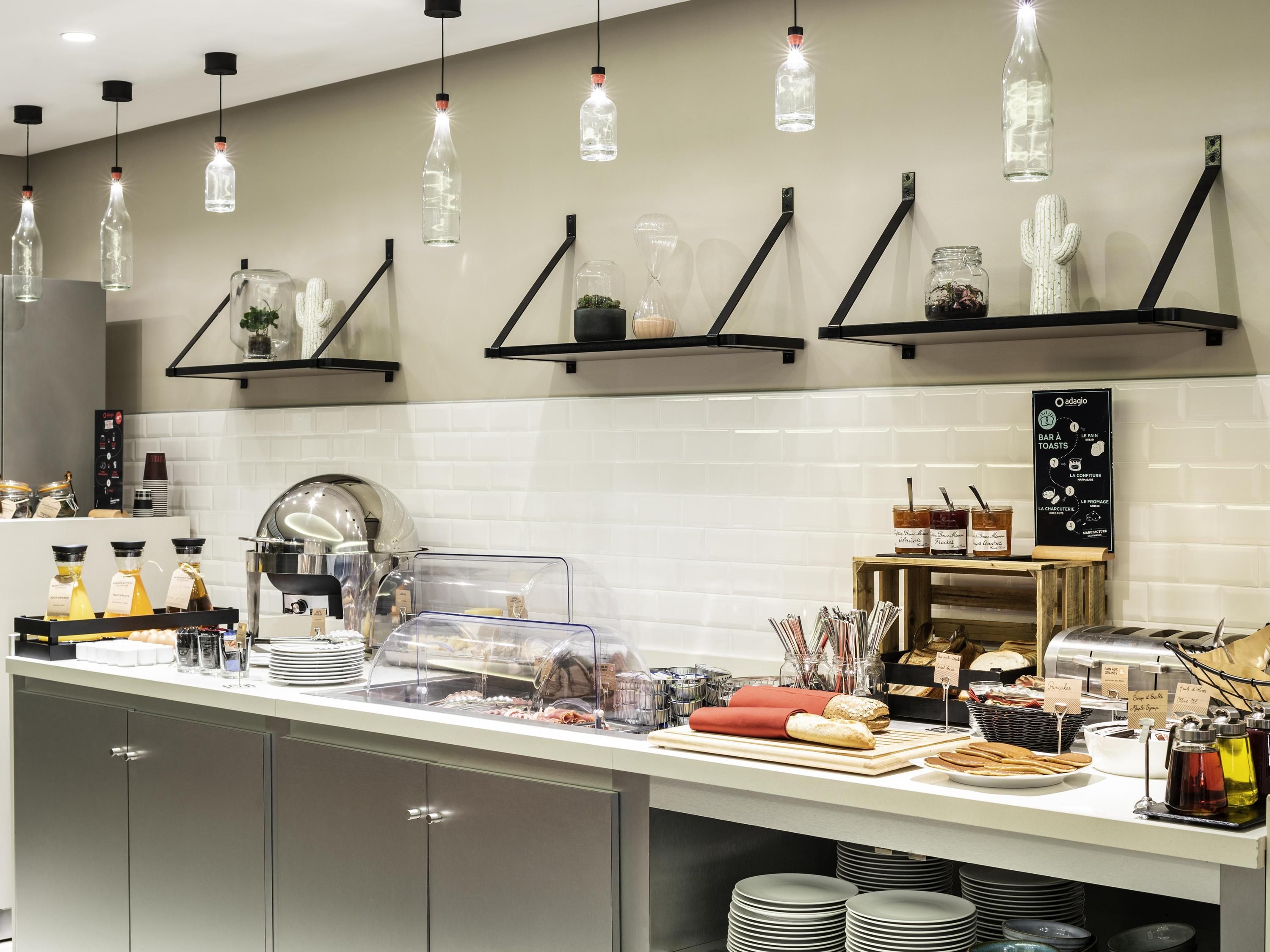 Una cocina moderna con cubierta de encimera blanca, lámparas colgantes negras y un panel de menú.