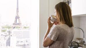 Una persona en una cocina con vista a la Torre Eiffel a través de una ventana.