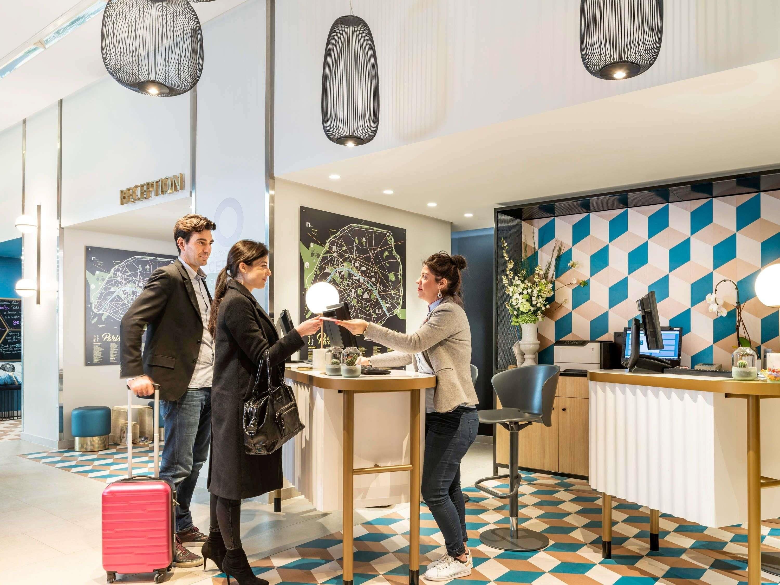 Un espace d’accueil au design moderne, comprenant un comptoir d’accueil, un ordinateur et un mur décoratif.