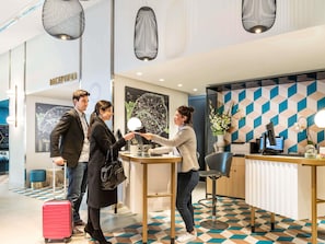 Un'area di accoglienza dal design moderno, con reception, computer e parete decorativa.