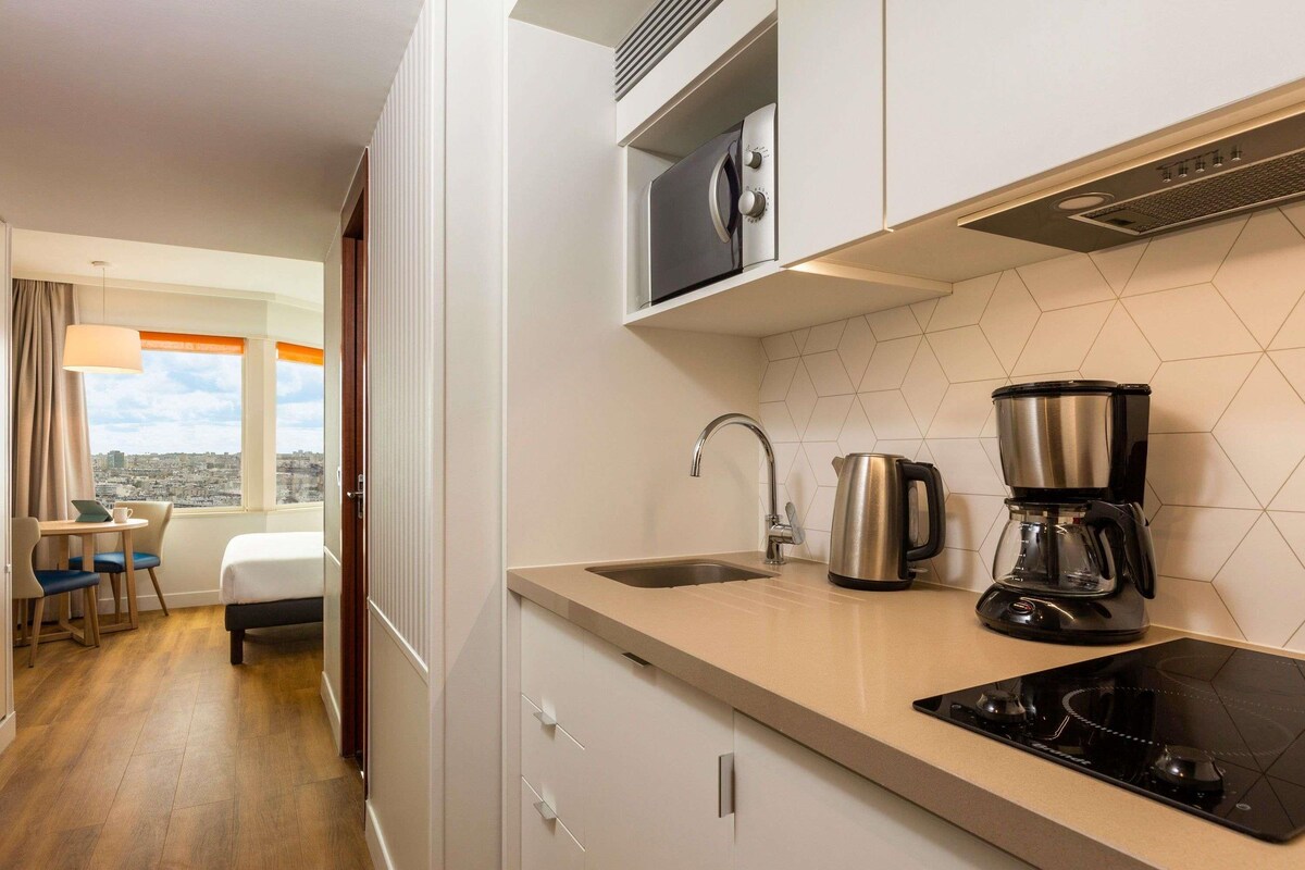 Una cocina moderna con estufa, cafetera y tetera.