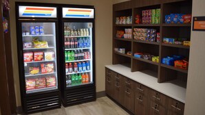 A vending machine area with two beverage dispensers and a snack shelf stocked with various products. - La Quinta Inn & Suites by Wyndham Middletown-Goshen (Middletown)