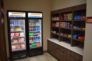 A vending machine area with two beverage dispensers and a snack shelf stocked with various products. - La Quinta Inn & Suites by Wyndham Middletown-Goshen (Middletown)