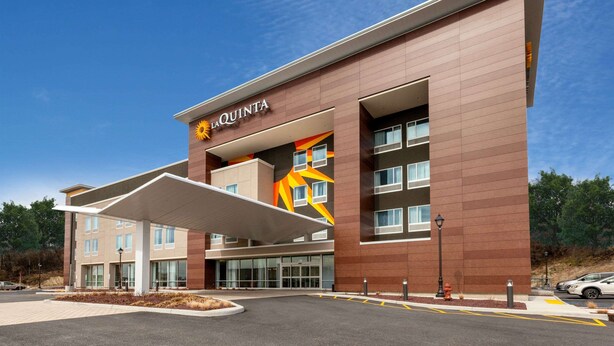 A modern hotel with a prominent 'La Quinta' sign, large windows, and a covered entrance area. - La Quinta Inn & Suites by Wyndham Middletown-Goshen (Middletown)