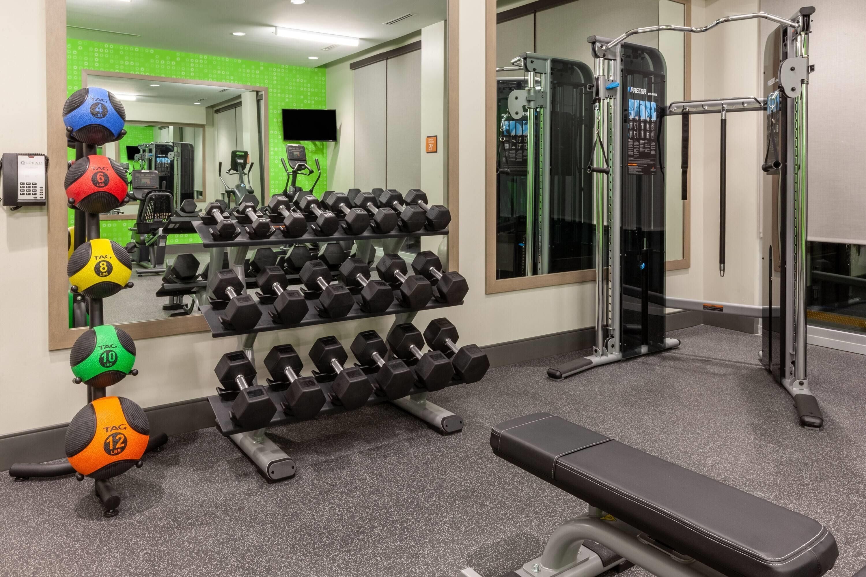 A gym with various weightlifting equipment, including dumbbells and a bench.