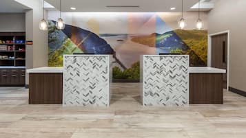 A reception area with a modern design, featuring a large wall mural, two reception counters with patterned backdrops, and a storage area with shelves on the left.