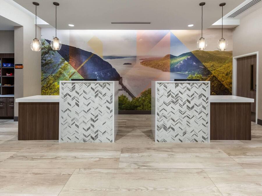 A reception area with a modern design, featuring a large wall mural, two reception counters with patterned backdrops, and a storage area with shelves on the left.
