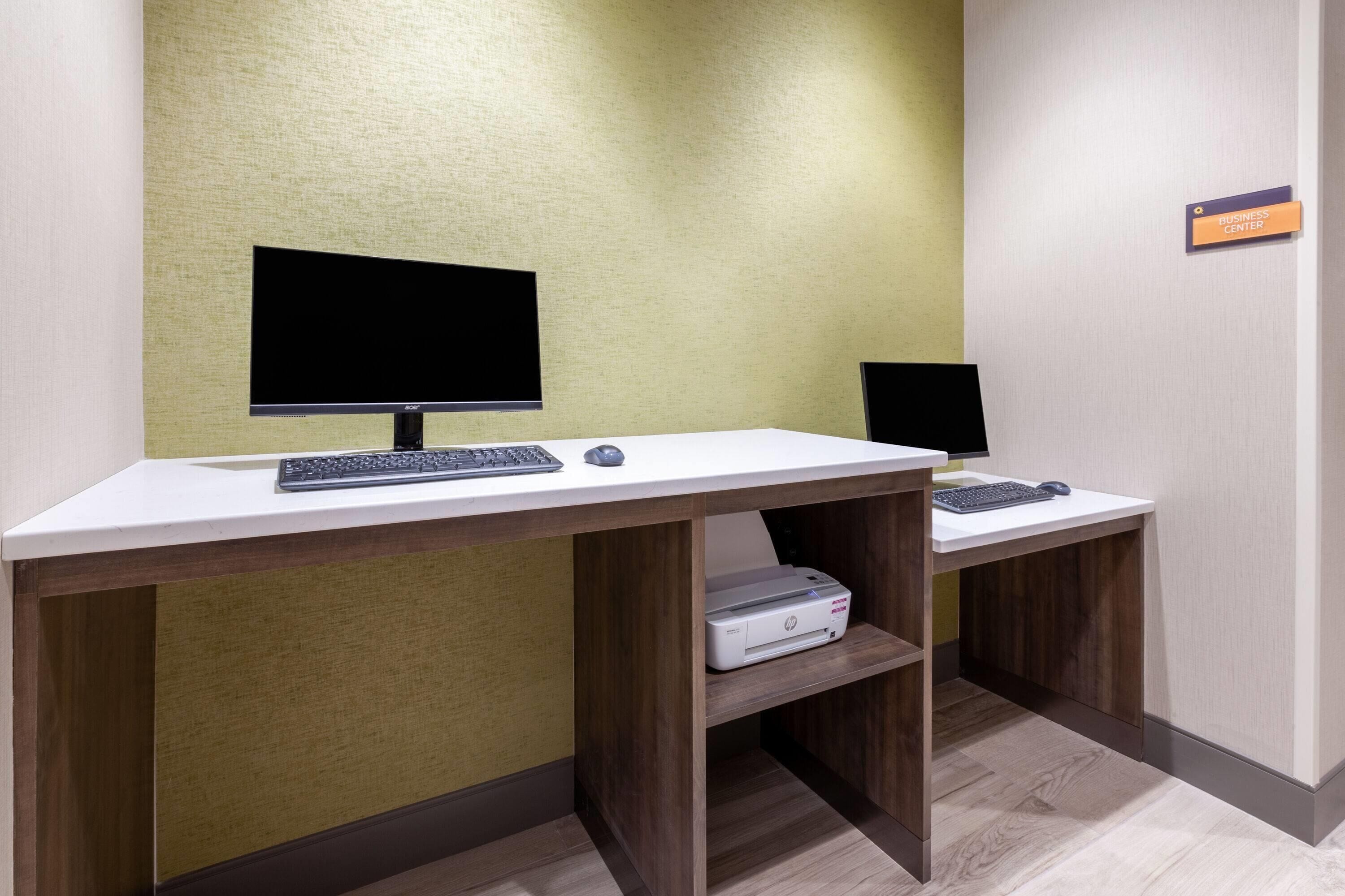 Un'area di lavoro in hotel con due scrivanie, ognuna dotata di computer, tastiera e mouse.