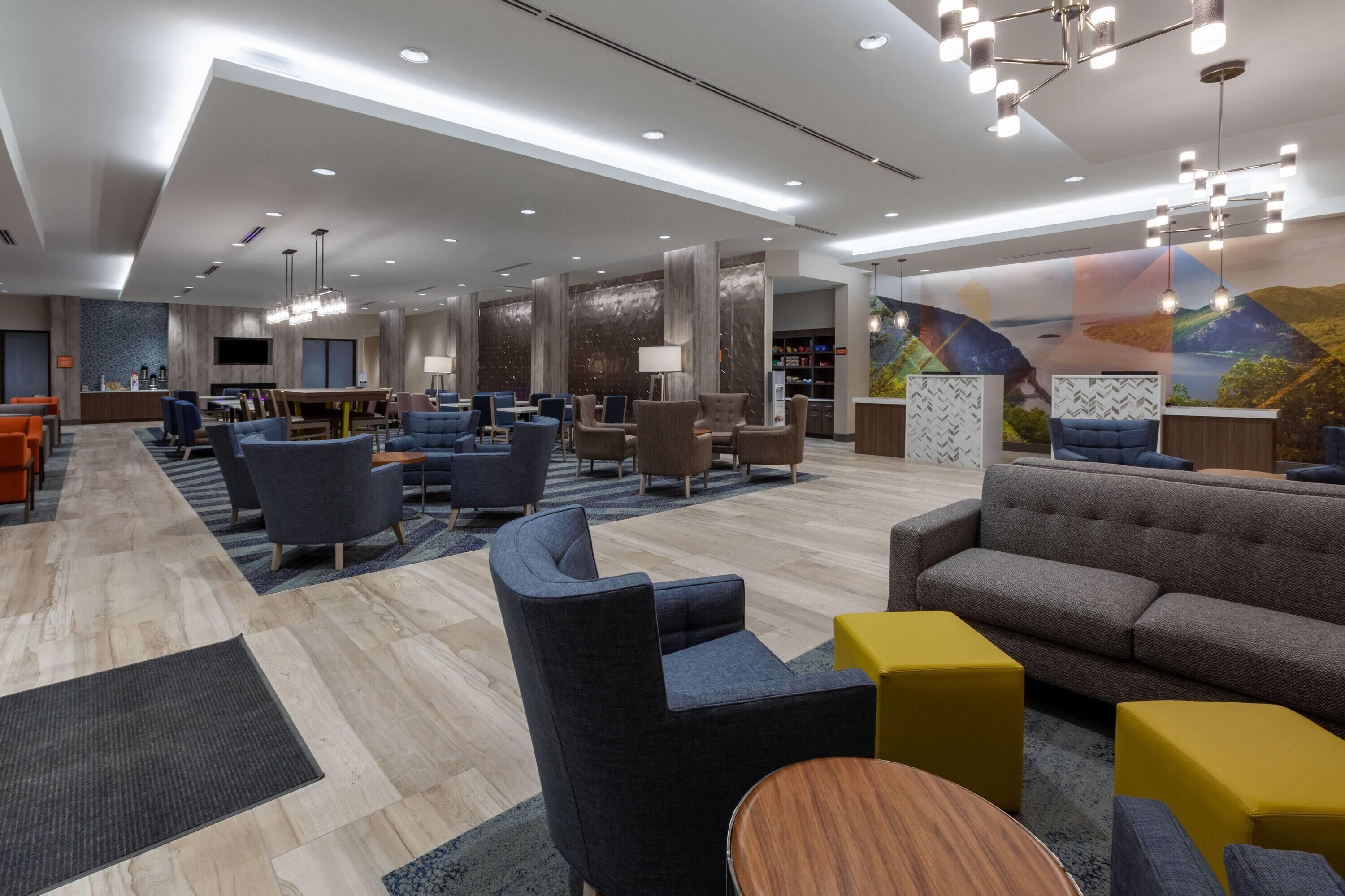 En moderne hotellobby med siddeområder, en reception og et stort mural.