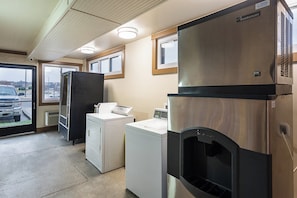 A laundromat with various appliances including a large stainless steel refrigerator, a washing machine, and a dryer. - Red Roof Inn PLUS+ Nashville North - Goodlettsville (Goodlettsville)