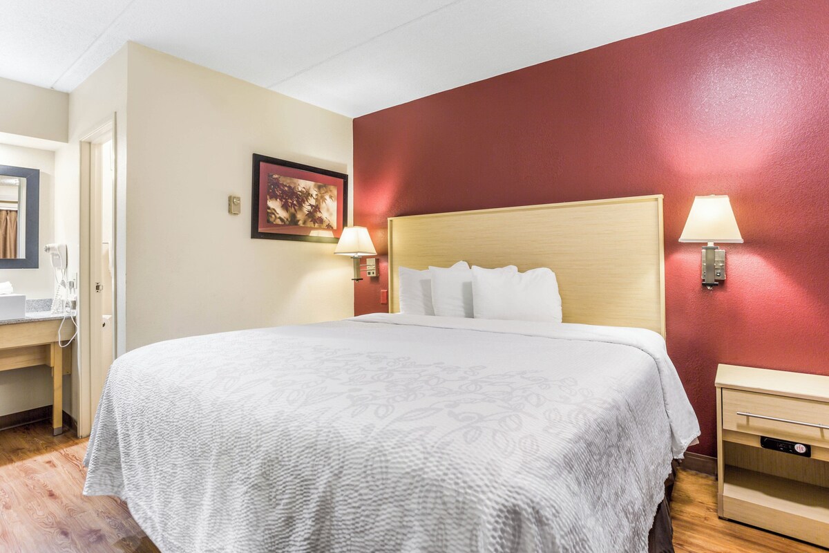 A hotel room with a large bed, bedside lamps, a desk, and a door.