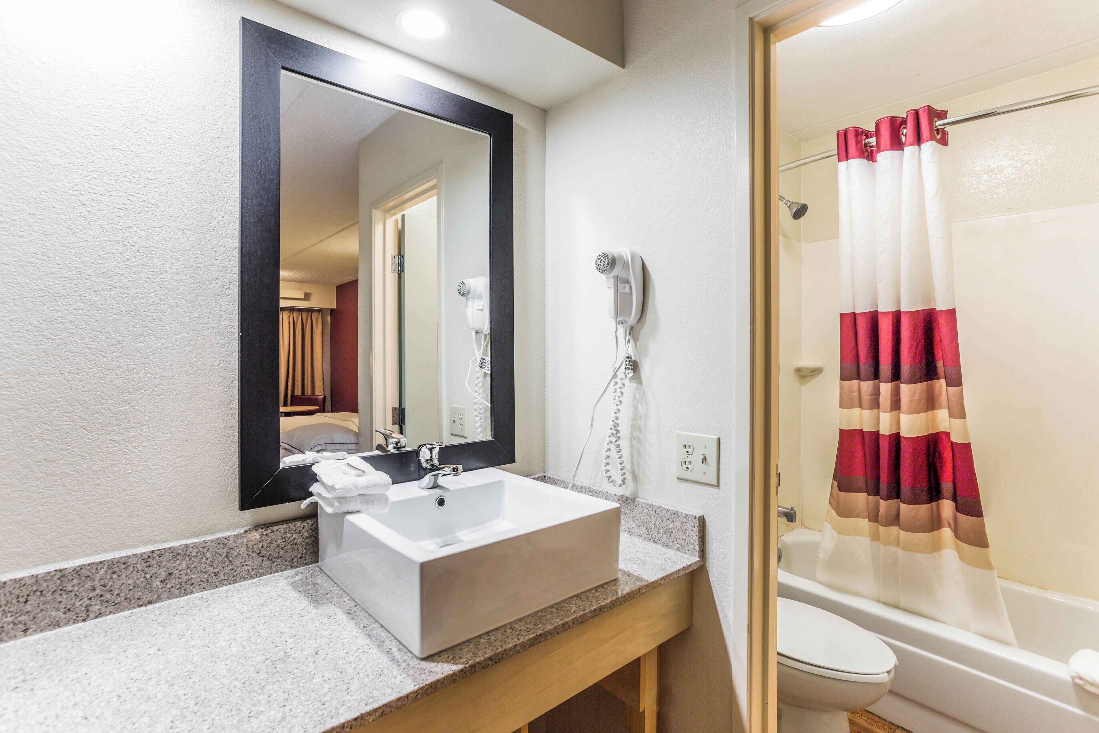 A bathroom with a white sink, a mirror, a hairdryer, and a shower curtain.
