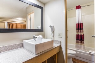 Un baño con un lavabo blanco, un espejo, un secador de pelo y una cortina de ducha.