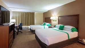 Een hotelkamer met twee bedden, een bureau, een stoel, een televisie en een raam met gordijnen.