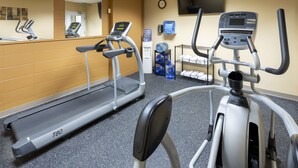 Een fitnessruimte met loopbanden, een elliptische trainer en een watervoorziening.