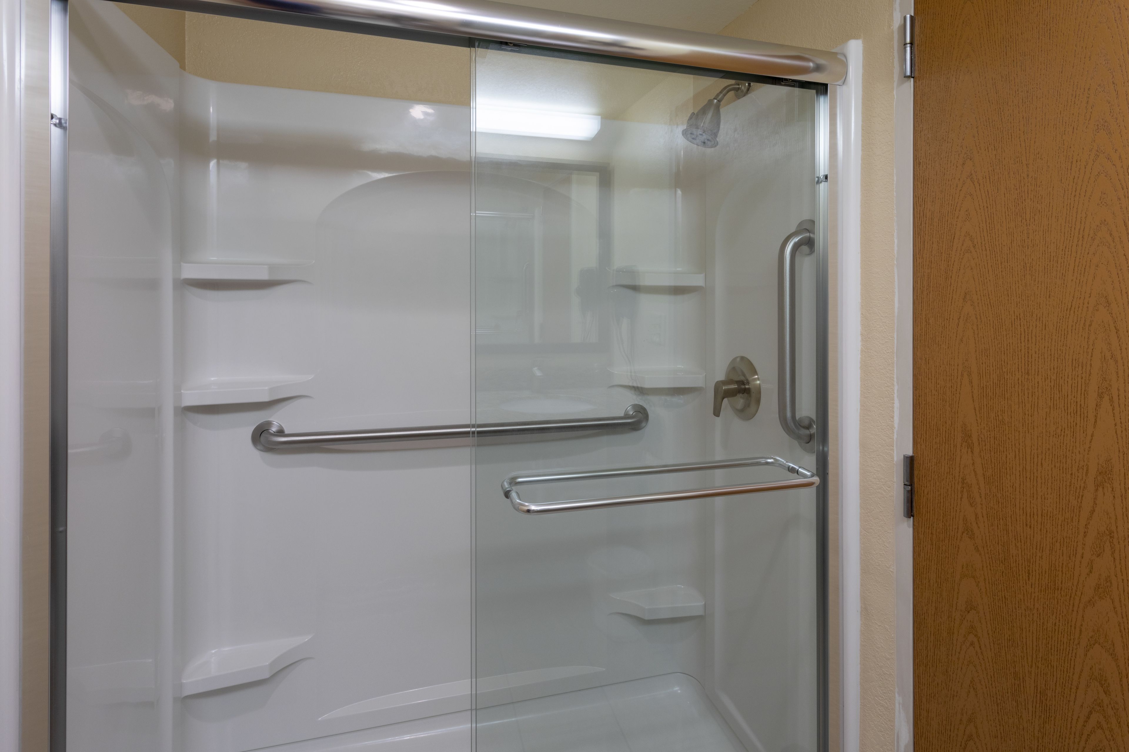 Eine Duschkabine aus Glas mit einer Metallgriffstange und einer Dusche.