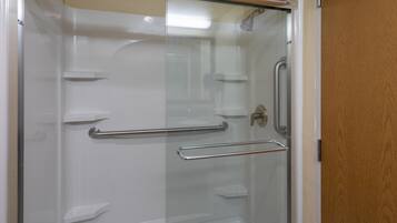 Eine Duschkabine aus Glas mit einer Metallgriffstange und einer Dusche.